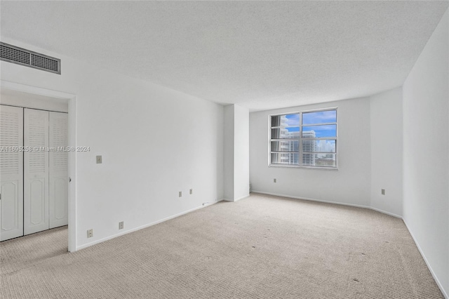 unfurnished bedroom featuring light colored carpet and a textured ceiling