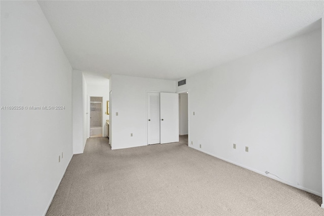 unfurnished bedroom featuring light carpet and ensuite bathroom