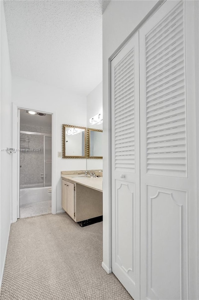 bathroom with vanity, a textured ceiling, and combined bath / shower with glass door