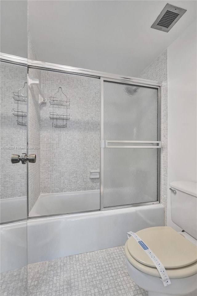 bathroom featuring tile patterned floors, toilet, and shower / bath combination with glass door