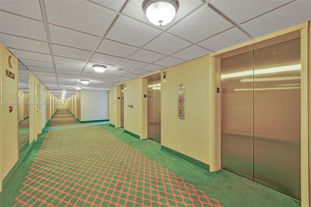 corridor with elevator, light carpet, and a drop ceiling