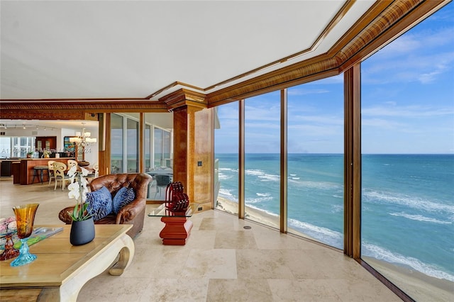 unfurnished living room featuring a water view, ornamental molding, a view of the beach, and an inviting chandelier