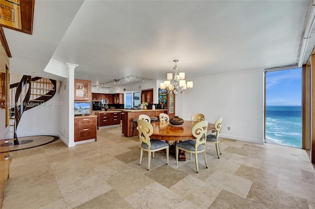 dining space with track lighting, floor to ceiling windows, and a notable chandelier