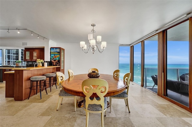 dining area with floor to ceiling windows, a wealth of natural light, a water view, and a notable chandelier