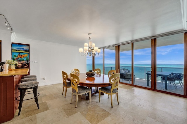 dining area featuring rail lighting, a water view, an inviting chandelier, and expansive windows