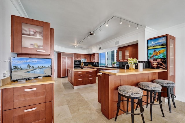 kitchen featuring kitchen peninsula, backsplash, crown molding, and a breakfast bar area