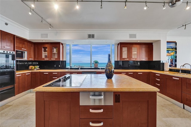 kitchen featuring black appliances, a kitchen island, ornamental molding, and tasteful backsplash