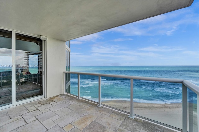 balcony with a water view and a view of the beach