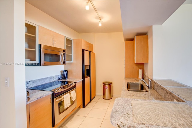 kitchen with sink, light tile patterned floors, light brown cabinetry, light stone counters, and stainless steel appliances