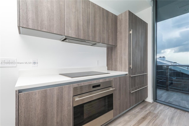 kitchen featuring black electric stovetop, oven, and light wood-type flooring