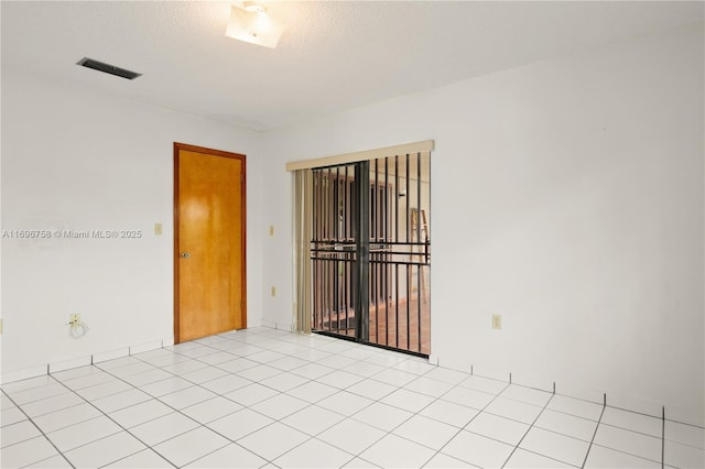 unfurnished room with a textured ceiling and light tile patterned flooring