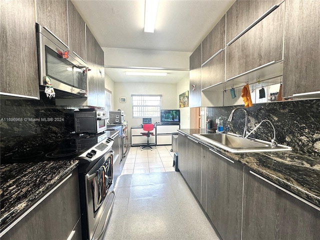 kitchen featuring sink, stainless steel appliances, dark stone countertops, decorative backsplash, and light tile patterned flooring