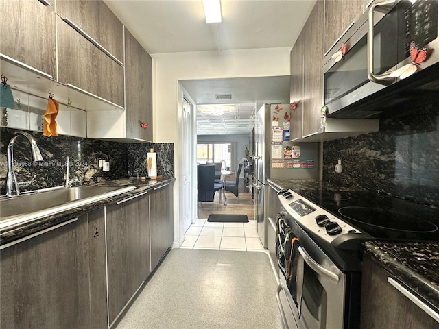 kitchen featuring appliances with stainless steel finishes, tasteful backsplash, dark brown cabinets, sink, and light tile patterned flooring