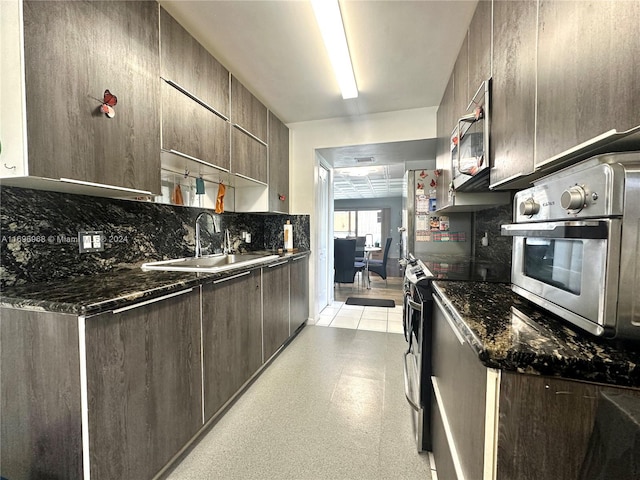 kitchen featuring dark brown cabinets, sink, appliances with stainless steel finishes, and dark stone counters