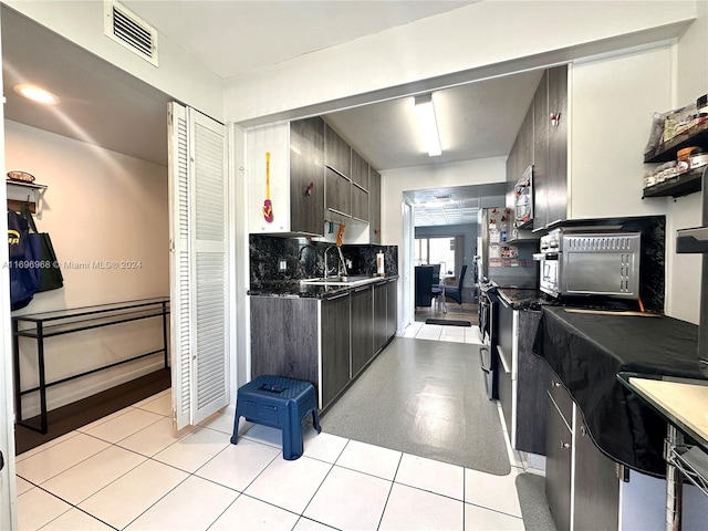 kitchen with dark brown cabinets, light tile patterned floors, and sink