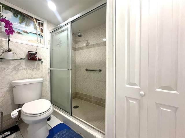 bathroom with tile patterned floors, a shower with shower door, tile walls, and toilet