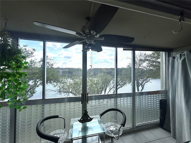 sunroom / solarium with ceiling fan and a water view