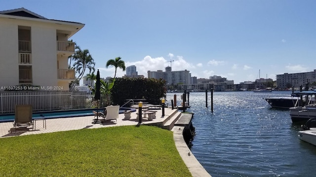 dock area with a lawn, a patio area, a water view, and a fenced in pool