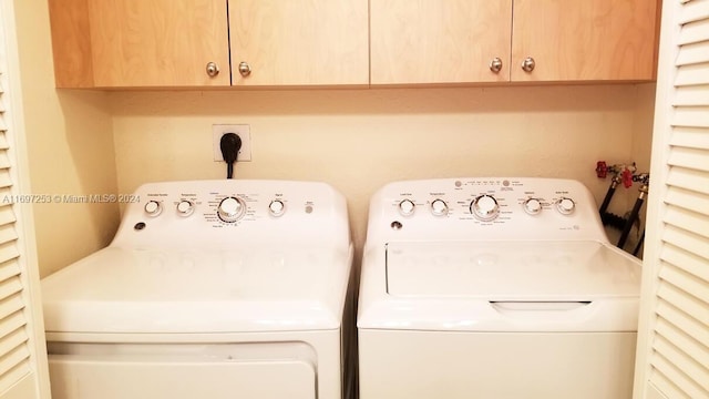 clothes washing area with cabinets and washer and dryer