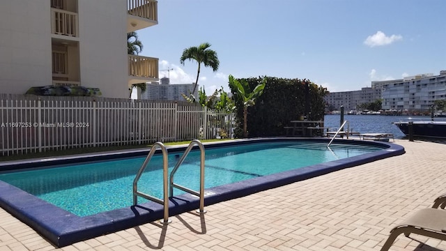 view of pool with a water view and a patio