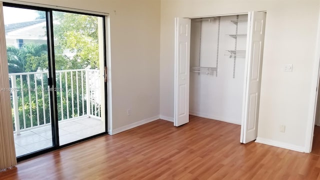 unfurnished bedroom featuring hardwood / wood-style flooring, access to exterior, and a closet