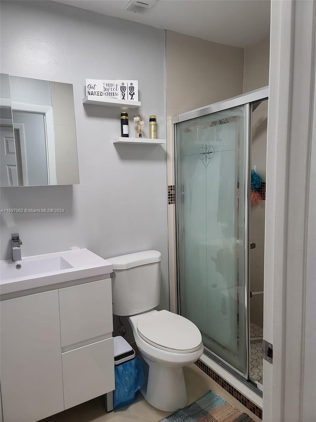 bathroom featuring tile patterned flooring, vanity, a shower with door, and toilet