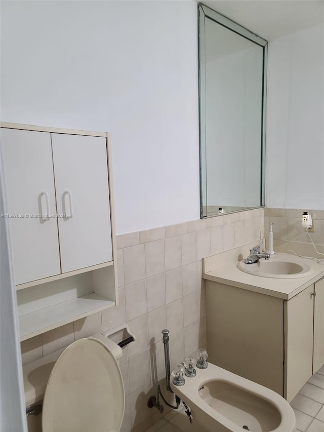 bathroom with tile patterned floors, vanity, a bidet, tile walls, and toilet