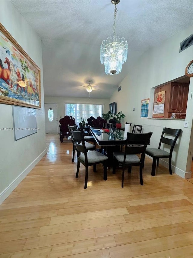 dining room featuring an inviting chandelier, light wood-style floors, visible vents, and lofted ceiling