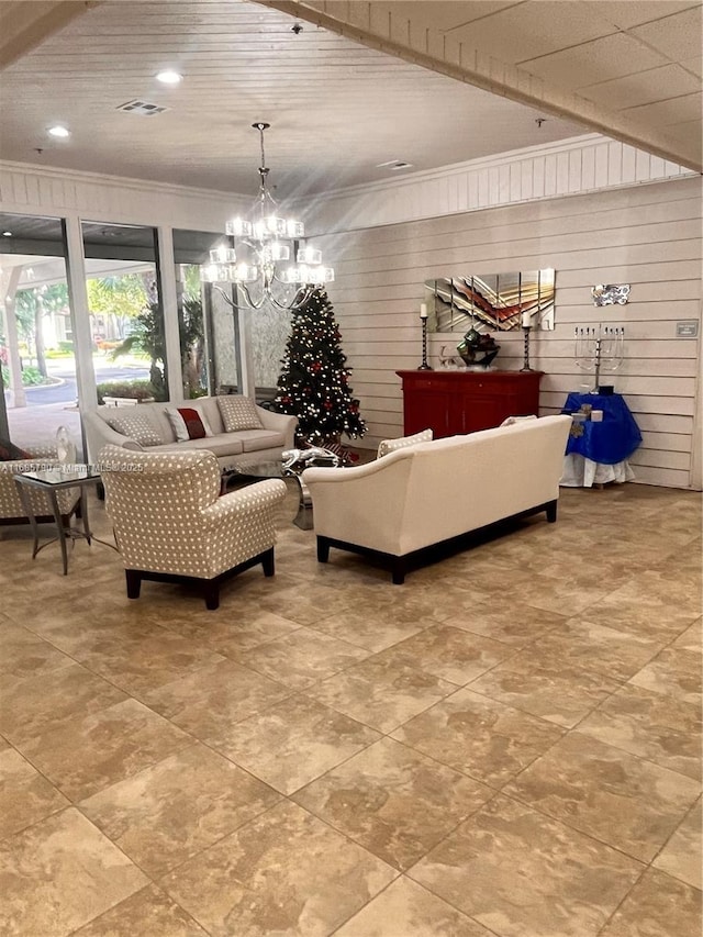 living area featuring visible vents, wooden walls, ornamental molding, and a notable chandelier