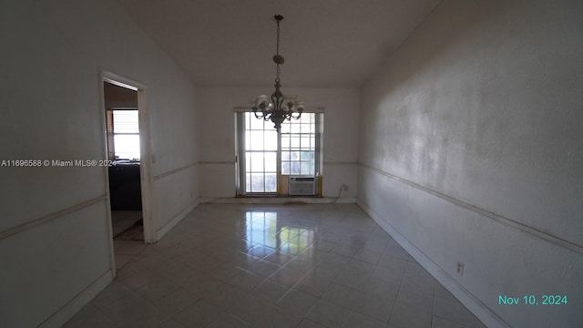 spare room with tile patterned flooring, a notable chandelier, lofted ceiling, and a wealth of natural light