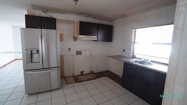 kitchen featuring stainless steel fridge, sink, and a textured ceiling