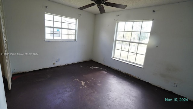 spare room with a textured ceiling, plenty of natural light, and ceiling fan