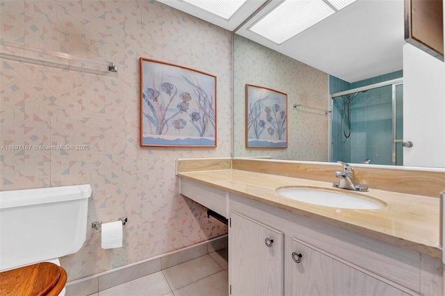 bathroom with a skylight, tile patterned flooring, vanity, an enclosed shower, and toilet