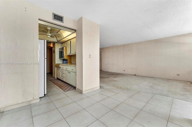 interior space with ceiling fan, light carpet, and a textured ceiling