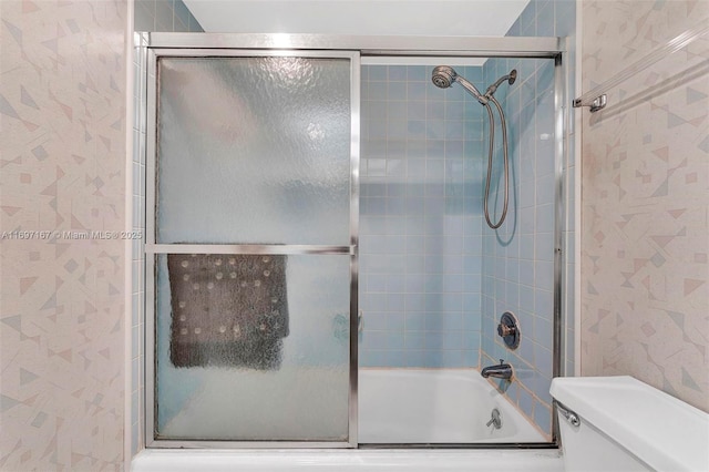 bathroom with combined bath / shower with glass door and toilet