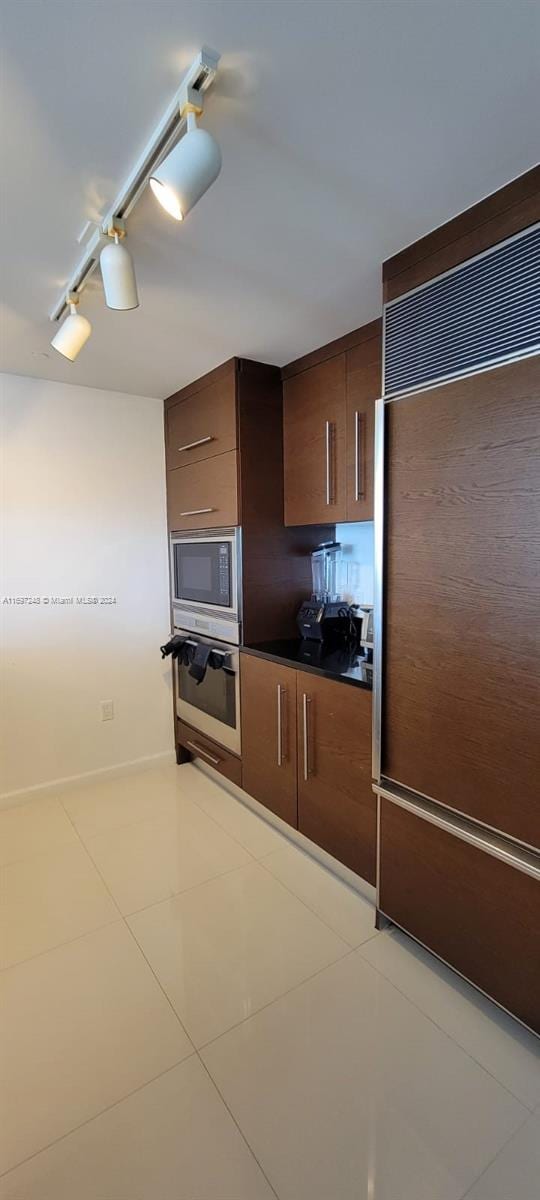 kitchen featuring light tile patterned floors, built in appliances, and rail lighting