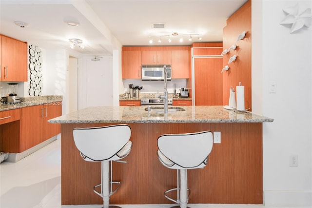 kitchen with a kitchen bar and light stone counters