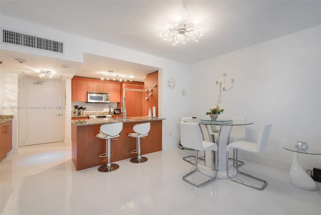 kitchen featuring stone counters, sink, kitchen peninsula, and light tile patterned flooring