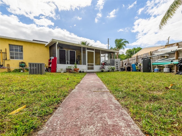 back of property featuring central AC unit, a lawn, and a sunroom