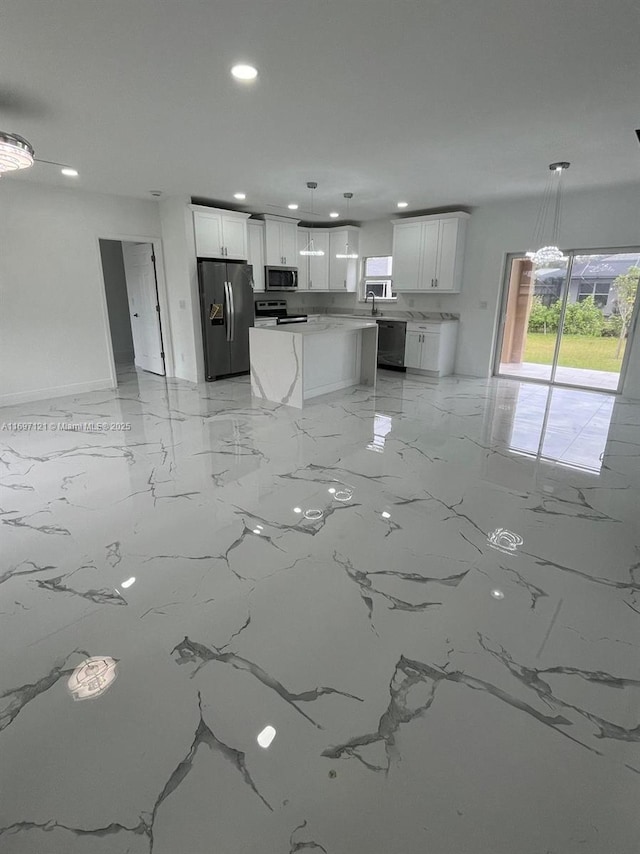 kitchen with stainless steel appliances, a kitchen island, sink, decorative light fixtures, and white cabinetry