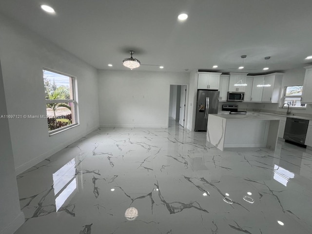 kitchen with stainless steel appliances, sink, decorative light fixtures, white cabinets, and a kitchen island