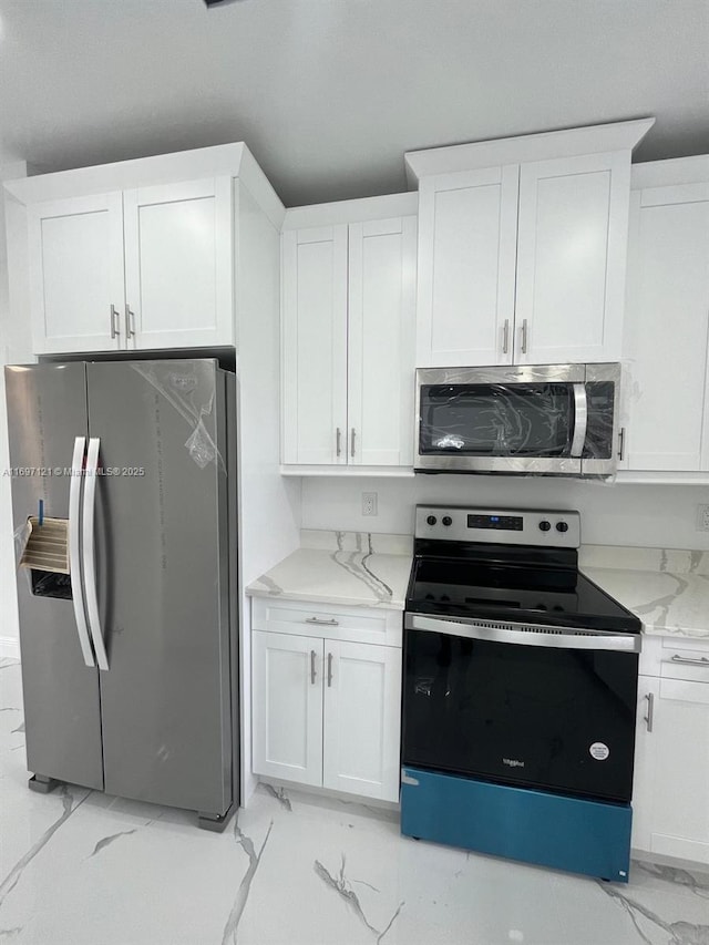 kitchen featuring light stone counters, white cabinets, and stainless steel appliances