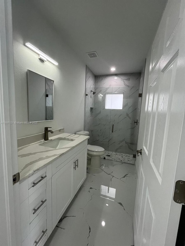 bathroom featuring vanity, toilet, and a shower with shower door