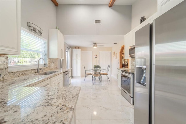 kitchen with white cabinets, sink, ceiling fan, appliances with stainless steel finishes, and beamed ceiling