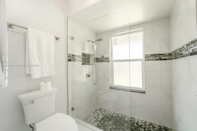 bathroom featuring a tile shower and toilet