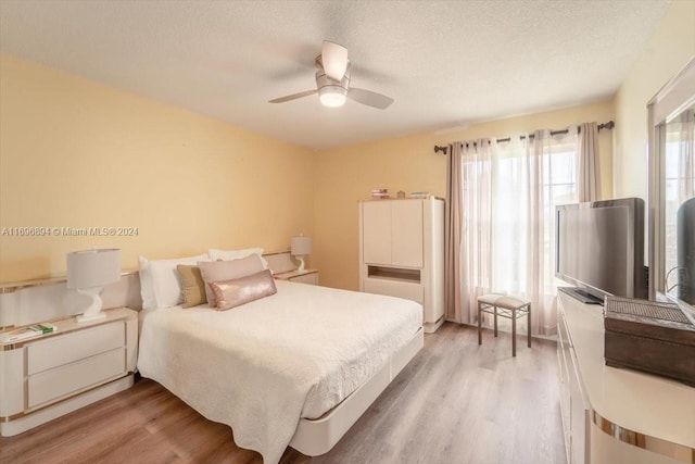 bedroom featuring ceiling fan, light wood-type flooring, and a textured ceiling