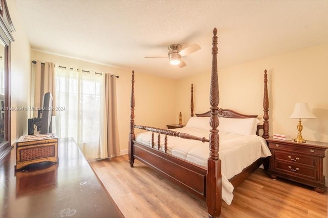 bedroom with ceiling fan, light wood-type flooring, and a textured ceiling