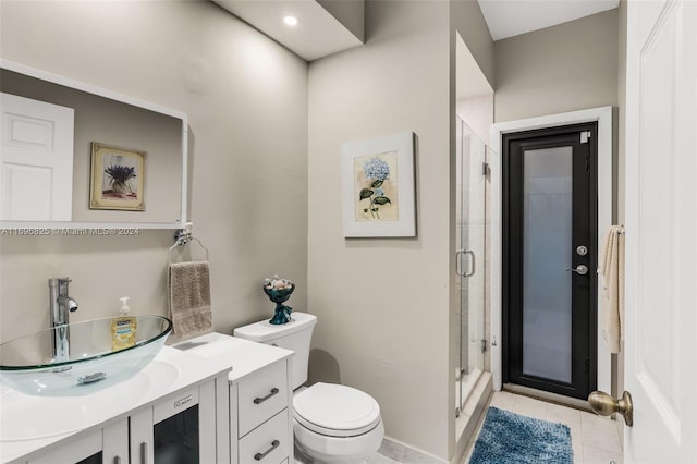 bathroom featuring tile patterned flooring, vanity, toilet, and a shower with door