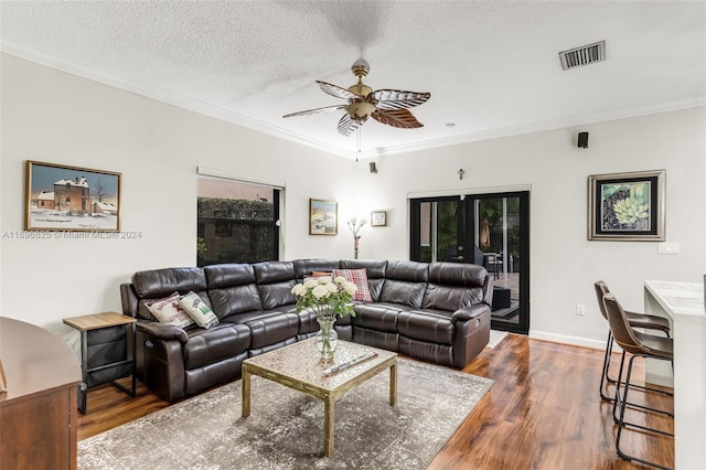 living room featuring french doors, wood-type flooring, a textured ceiling, and ornamental molding