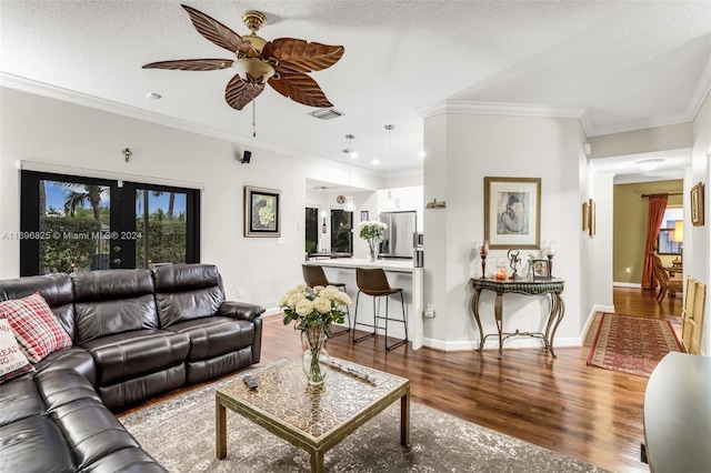 living room featuring hardwood / wood-style flooring, ceiling fan, ornamental molding, and a textured ceiling